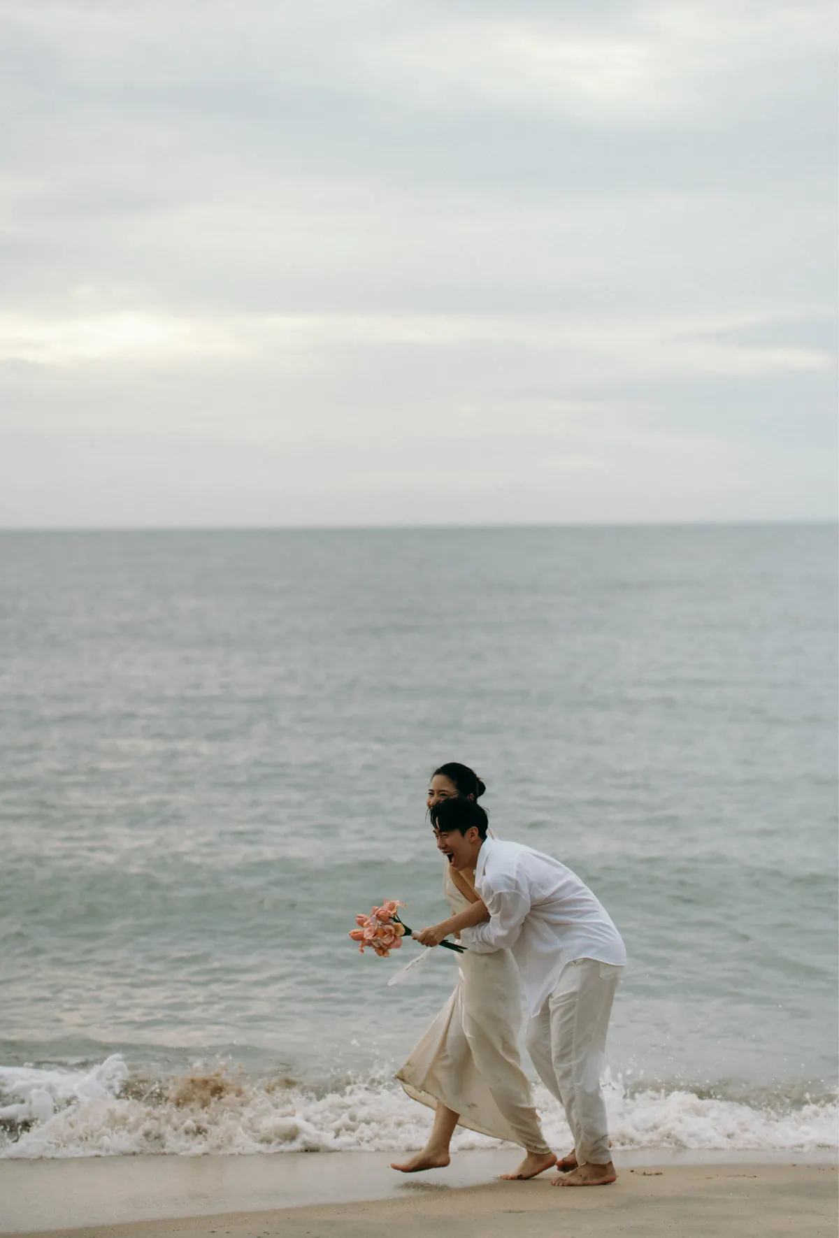 The couple running along the beach at the water's edge